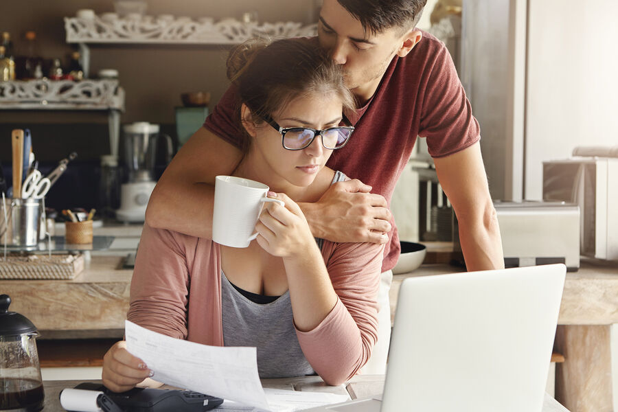 young-couple-having-credit-problem-bank-supportive-man-hugging-kissing-his-unhappy-wife-her-head-while-she-is-sitting-kitchen-table-front-laptop-pic_32ratio_900x600-900x600-93130.jpg